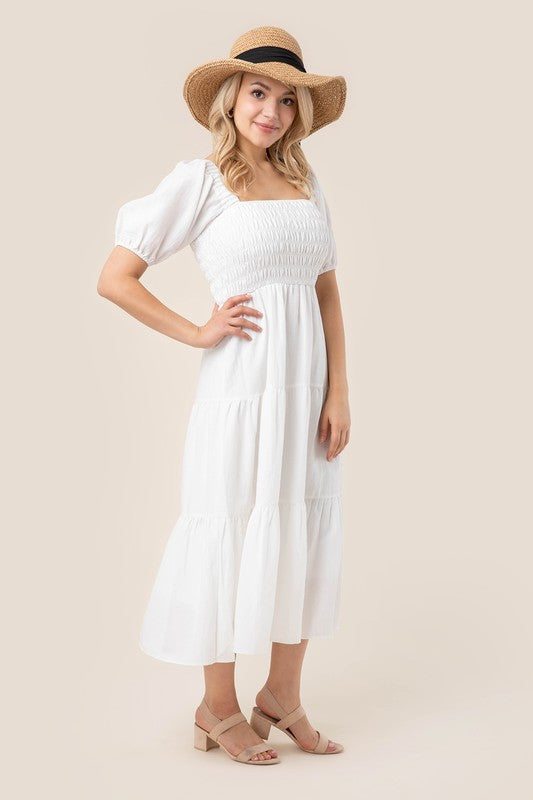 Embrace effortless elegance with this stunning maxi dress from Lilou. Featuring a smocked bodice that offers a flattering, fitted look, this dress is both chic and comfortable. The puff sleeves add a touch of vintage charm, while the tiered skirt creates a flowy silhouette perfect for any occasion. Whether you're attending a garden party, a beach wedding, or just enjoying a sunny day out, this dress will keep you looking stylish and feeling confident. Pair it with your favorite sandals and a wide-brimmed ha